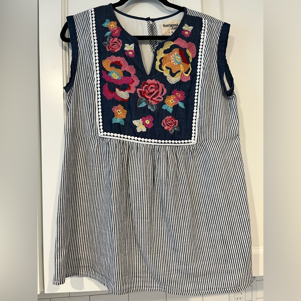 Sleeveless seer sucker top with embroidered flowers.